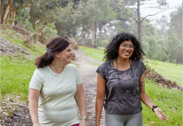 Two women walking outdoors together and talking.