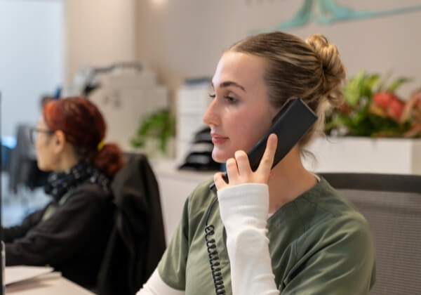Medical reception staff member speaking on the phone at The Banyan Medical Centre.